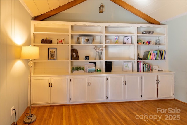 interior space featuring hardwood / wood-style flooring, ornamental molding, beam ceiling, and built in features