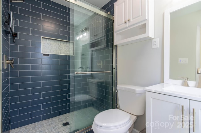 bathroom featuring vanity, a shower with door, and toilet