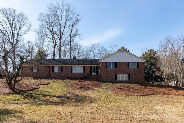 view of front of house with a front yard, brick siding, and a chimney