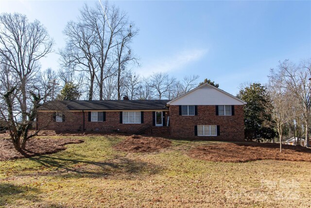 view of front of home featuring brick siding and a lawn