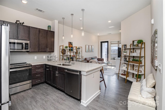 kitchen featuring sink, hanging light fixtures, kitchen peninsula, and appliances with stainless steel finishes