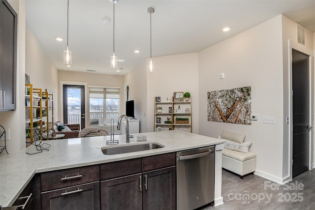 kitchen with pendant lighting, sink, stainless steel dishwasher, light stone countertops, and dark brown cabinets