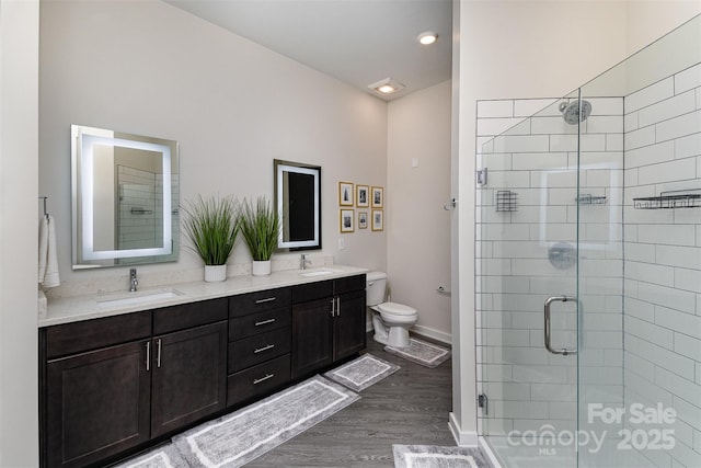 bathroom with a shower with door, vanity, wood-type flooring, and toilet