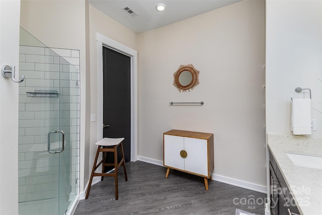 bathroom featuring hardwood / wood-style flooring, vanity, and a shower with door