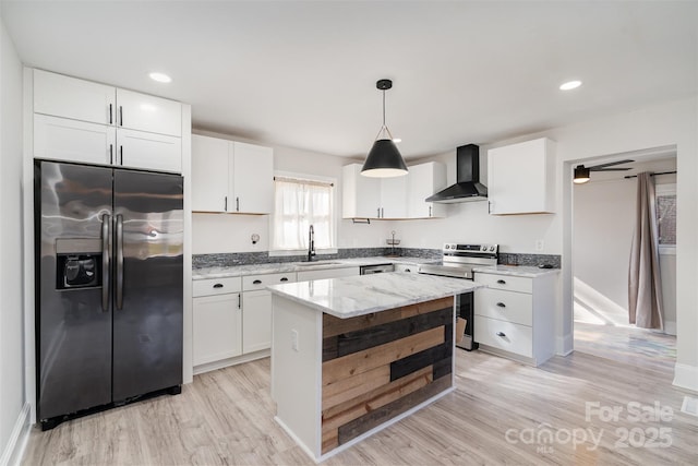 kitchen with white cabinetry, decorative light fixtures, appliances with stainless steel finishes, a kitchen island, and wall chimney range hood