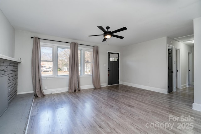 unfurnished living room with a fireplace, ceiling fan, and light wood-type flooring