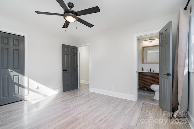 bedroom with connected bathroom, light hardwood / wood-style flooring, a closet, and ceiling fan