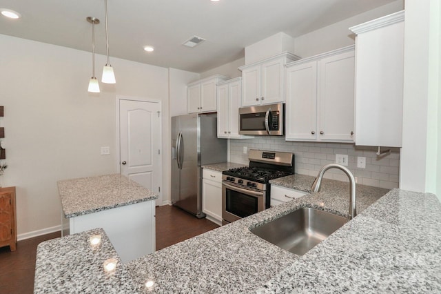 kitchen with white cabinetry, sink, light stone countertops, and appliances with stainless steel finishes