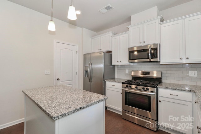 kitchen with white cabinetry, light stone counters, stainless steel appliances, and a kitchen island