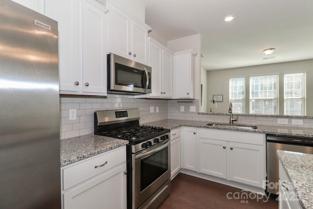 kitchen featuring light stone counters, sink, stainless steel appliances, and white cabinets