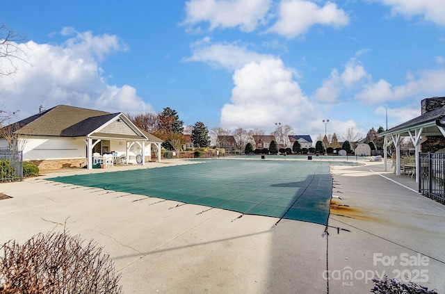 community pool with fence, a gazebo, and a patio