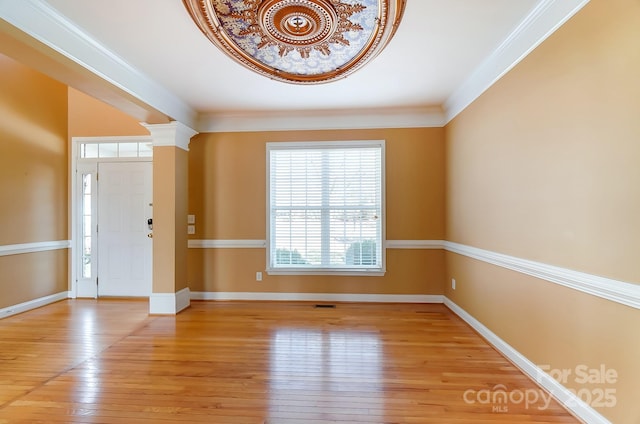 foyer entrance featuring ornamental molding, light wood-type flooring, decorative columns, and baseboards