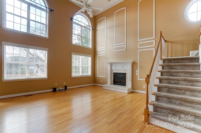 unfurnished living room featuring a wealth of natural light, a fireplace, stairway, and hardwood / wood-style flooring