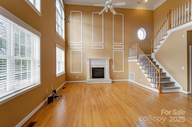 unfurnished living room with hardwood / wood-style flooring, baseboards, a wealth of natural light, and a glass covered fireplace