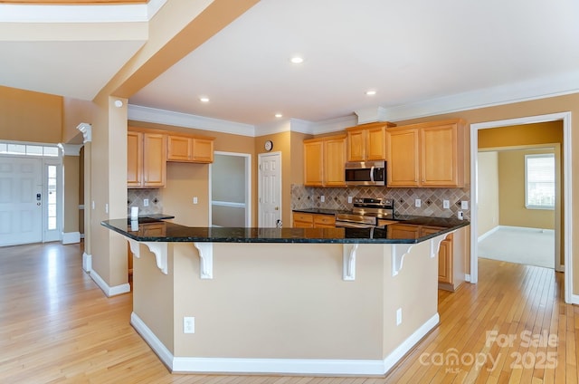 kitchen with appliances with stainless steel finishes, a breakfast bar, and light wood finished floors