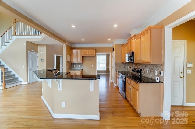 kitchen with appliances with stainless steel finishes, a breakfast bar area, and light wood-style flooring