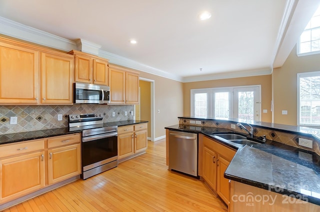 kitchen with stainless steel appliances, light wood finished floors, a sink, and crown molding