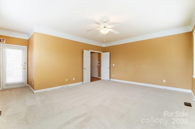 spare room featuring a ceiling fan, light carpet, crown molding, and baseboards