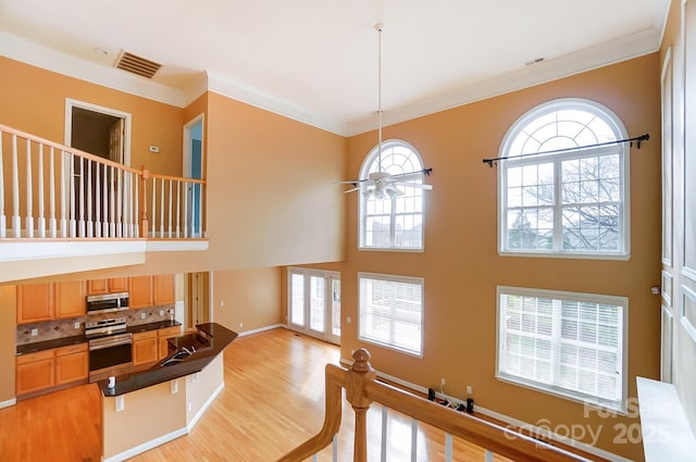 interior space featuring dark countertops, stainless steel microwave, visible vents, a ceiling fan, and ornamental molding