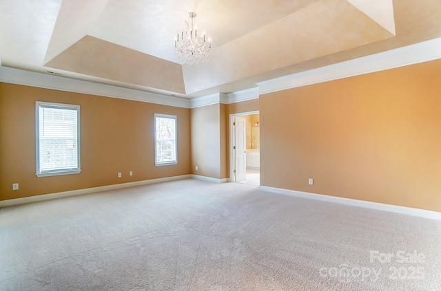 spare room featuring a chandelier, a tray ceiling, light colored carpet, and baseboards