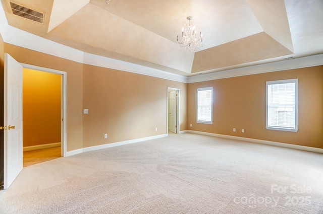 carpeted empty room with a tray ceiling, a healthy amount of sunlight, visible vents, and an inviting chandelier