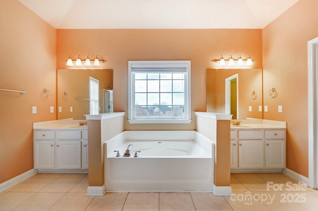 bathroom with two vanities, a garden tub, baseboards, and tile patterned floors