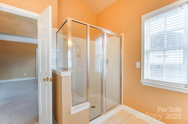 bathroom with tile patterned flooring, a shower stall, baseboards, and a wealth of natural light