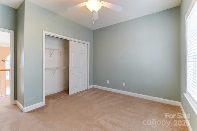 unfurnished bedroom with light carpet, a ceiling fan, baseboards, and a closet