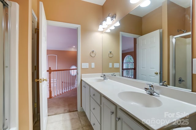 bathroom with double vanity, tile patterned flooring, a sink, and a shower with door