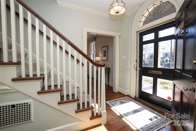 foyer entrance with crown molding and dark wood-type flooring