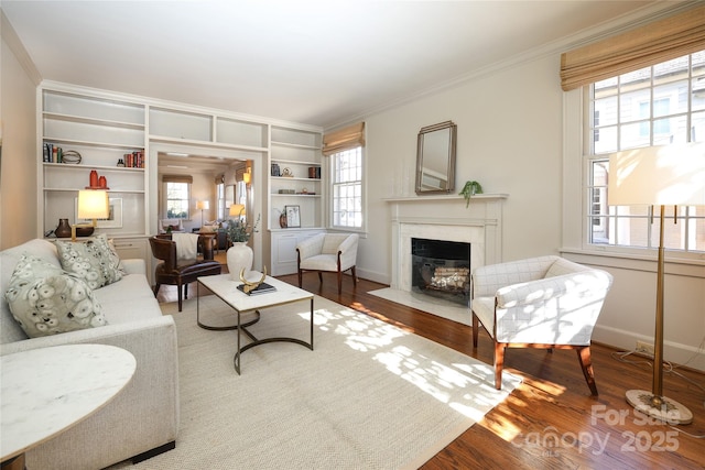 living room with crown molding, plenty of natural light, a high end fireplace, and wood-type flooring