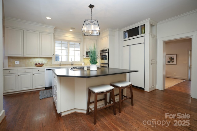 kitchen featuring stainless steel appliances, dark hardwood / wood-style floors, a center island, and white cabinets