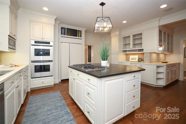 kitchen featuring decorative light fixtures, white cabinetry, a center island, built in appliances, and dark wood-type flooring