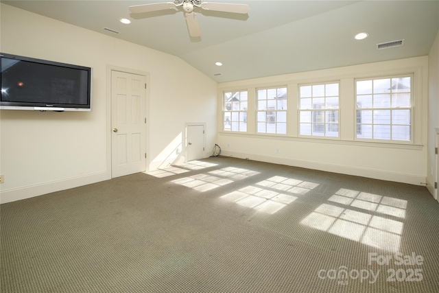 carpeted spare room featuring vaulted ceiling, ceiling fan, and plenty of natural light