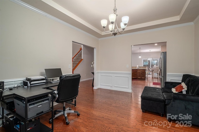 office area with an inviting chandelier, ornamental molding, wood-type flooring, and a tray ceiling