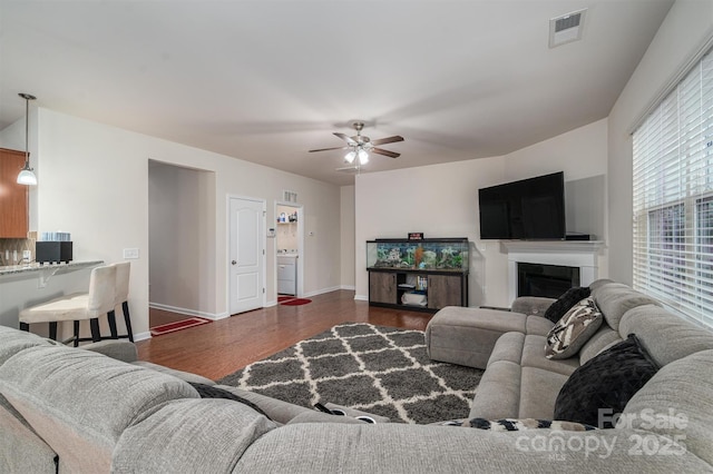 living room featuring dark wood-type flooring and ceiling fan