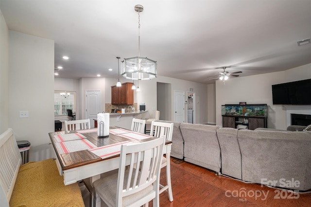 dining space with dark hardwood / wood-style flooring and ceiling fan with notable chandelier