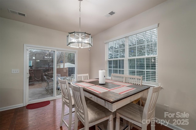 dining space with dark hardwood / wood-style flooring and a notable chandelier