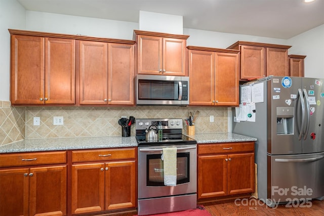 kitchen with stainless steel appliances, dark hardwood / wood-style floors, backsplash, and light stone counters