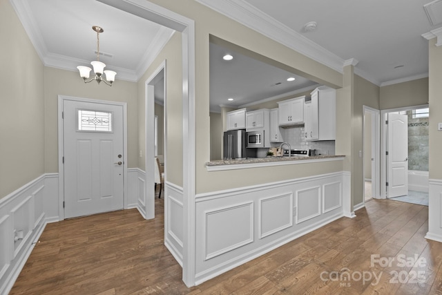 entryway featuring crown molding, dark hardwood / wood-style floors, sink, and an inviting chandelier