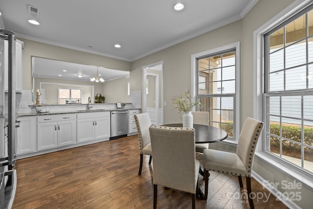 dining room featuring sink, crown molding, dark wood-type flooring, and a notable chandelier