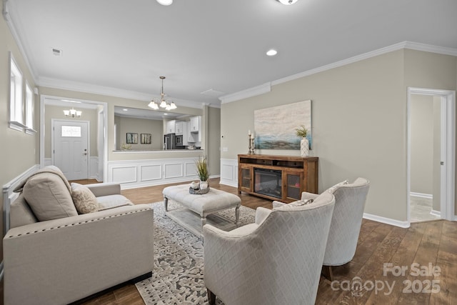 living room featuring hardwood / wood-style floors, crown molding, and a notable chandelier