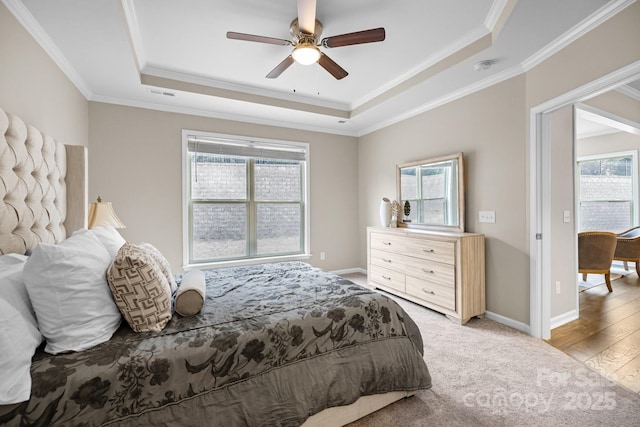 bedroom with a tray ceiling, ornamental molding, light hardwood / wood-style floors, and ceiling fan