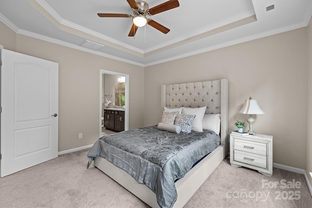 bedroom with ornamental molding, light colored carpet, ensuite bath, and a tray ceiling