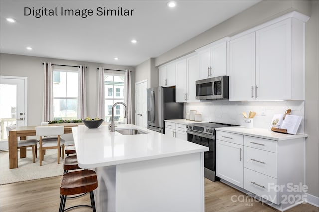 kitchen featuring appliances with stainless steel finishes, sink, a center island with sink, and white cabinets