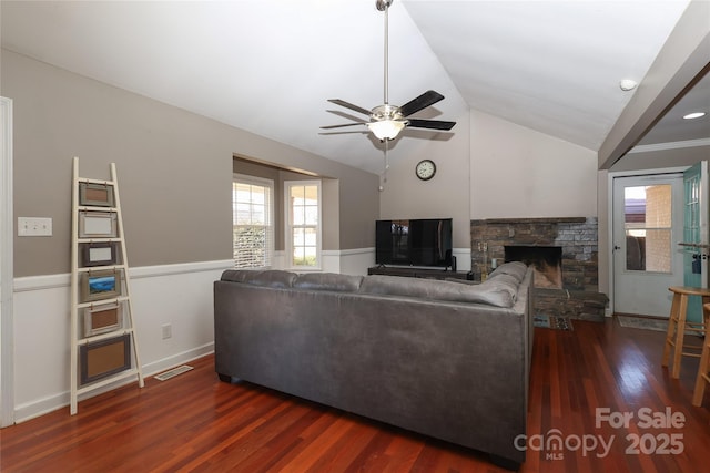 living room with vaulted ceiling, a stone fireplace, ceiling fan, and dark hardwood / wood-style flooring