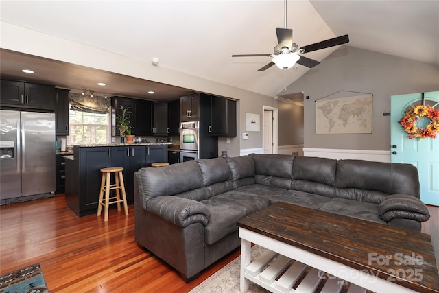 living room featuring ceiling fan, dark hardwood / wood-style flooring, and vaulted ceiling