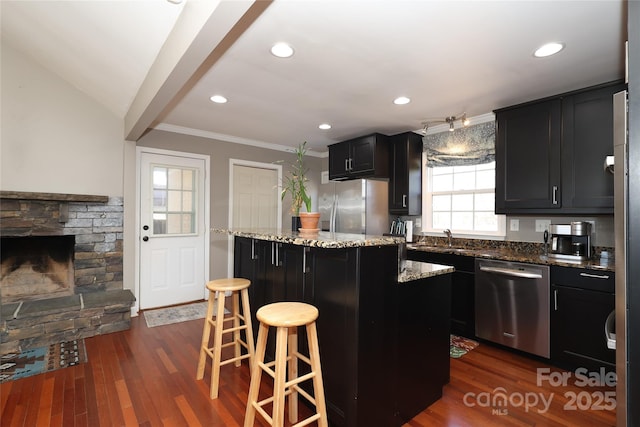 kitchen featuring appliances with stainless steel finishes, a kitchen breakfast bar, a center island, and stone countertops