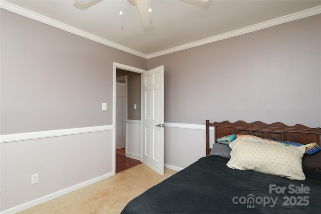 carpeted bedroom with ornamental molding and ceiling fan