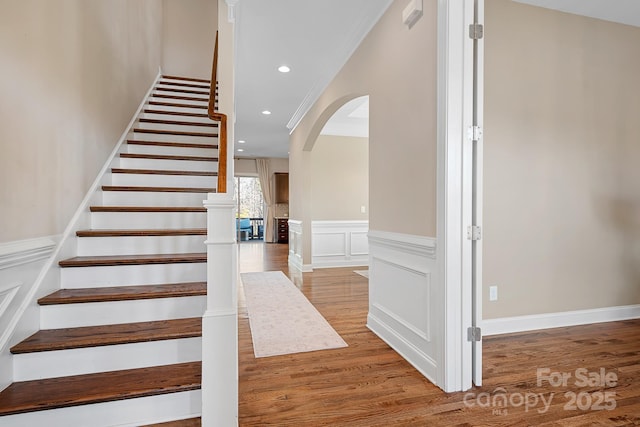 stairs with hardwood / wood-style flooring and ornamental molding